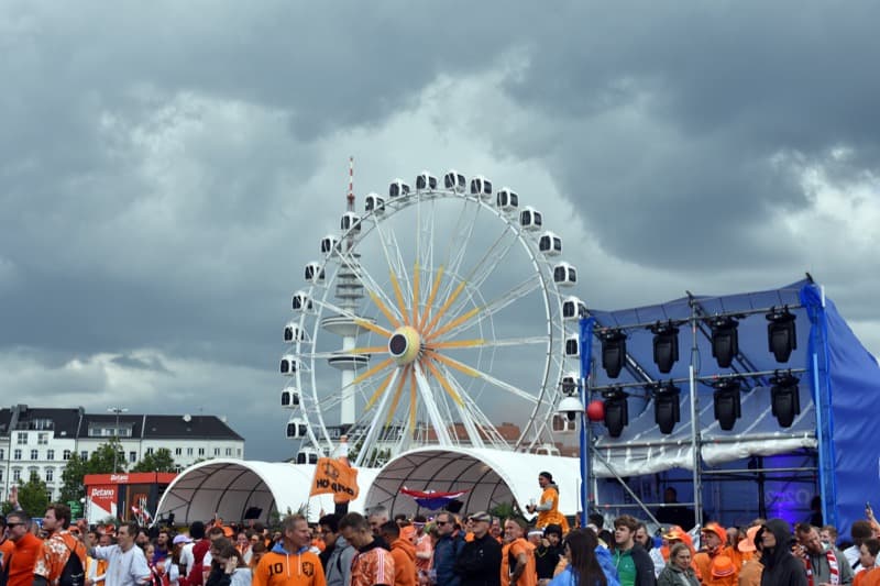 Ferris wheel and fans dressed in orange Netherlands gear at the Fan Fest on Hamburg's Heiligengeistfeld.