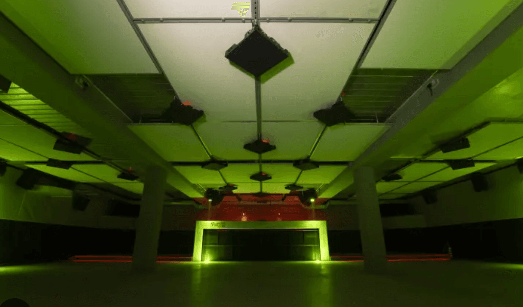 Interior of the Tokonoma club in green lighting with a stage and speakers.